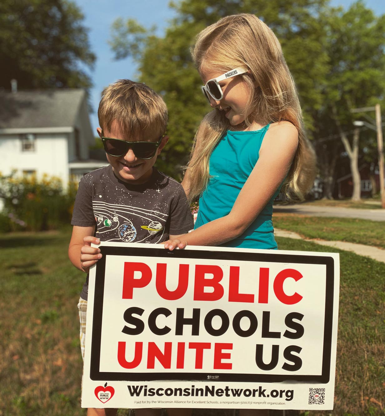 two children with a sign that says "Public Schools Unite Us"